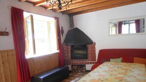 Ein gemütlicher Raum mit Kamin, Holzwänden, einer Bank und einem Bett mit floralem Überwurf.