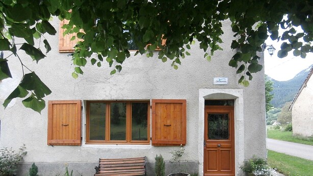 Ein rustikales Gebäude mit einer Bank, Holzläden und einer Tür.