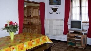 Ein Zimmer mit einem Holzkasten, einem Fernseher auf einem Holzständer, einer Heizung und einem Bild an der Wand.