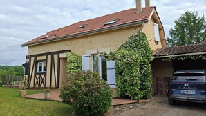 Une maison à deux étages avec un toit recouvert de tuiles rouges, un garage et une voiture garée devant.