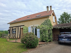 A two-story house with a red-tiled roof, a garage, and a parked car. - Beautiful abode with swimming pool nearby Sarlat, in the Perigord Noir (Coux Et Bigaroque-Mouzens)