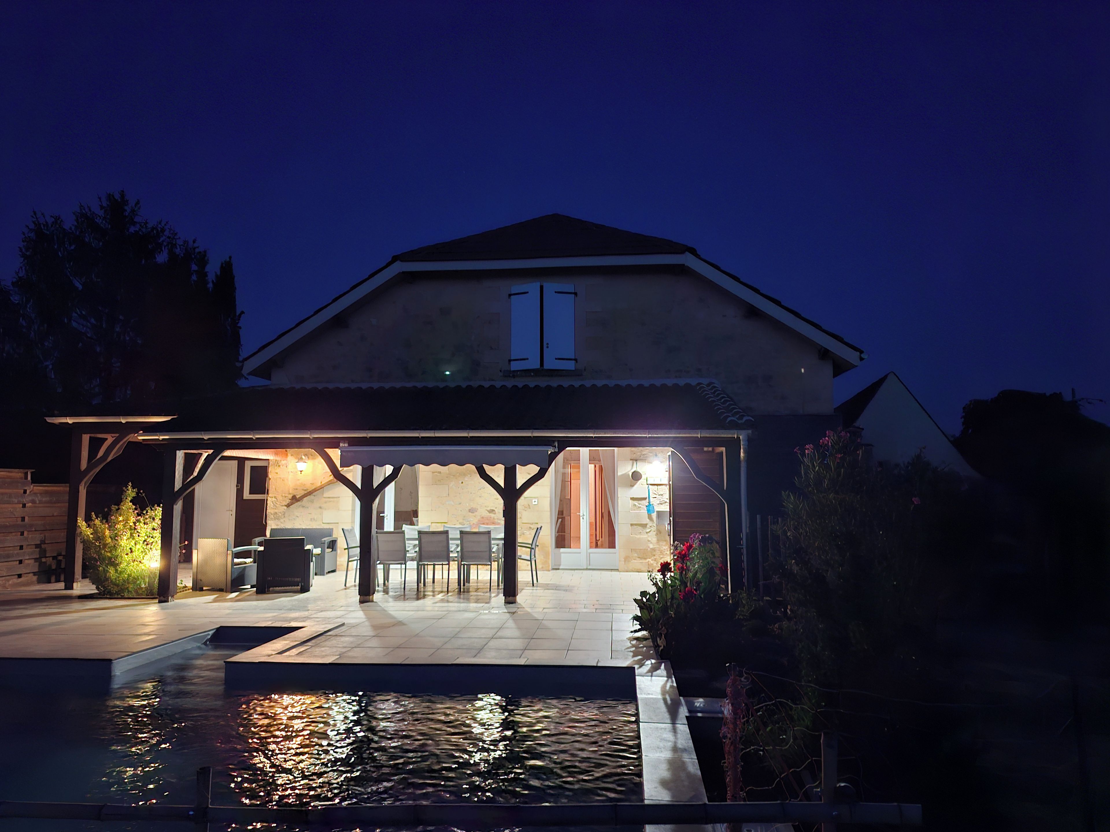 A house with a covered patio area, a swimming pool, and a garden.