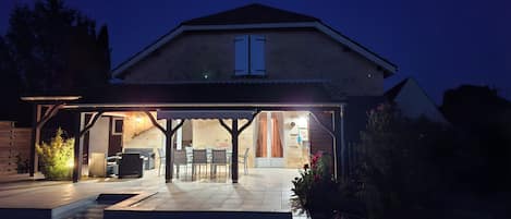 A house with a covered patio area, a swimming pool, and a garden.