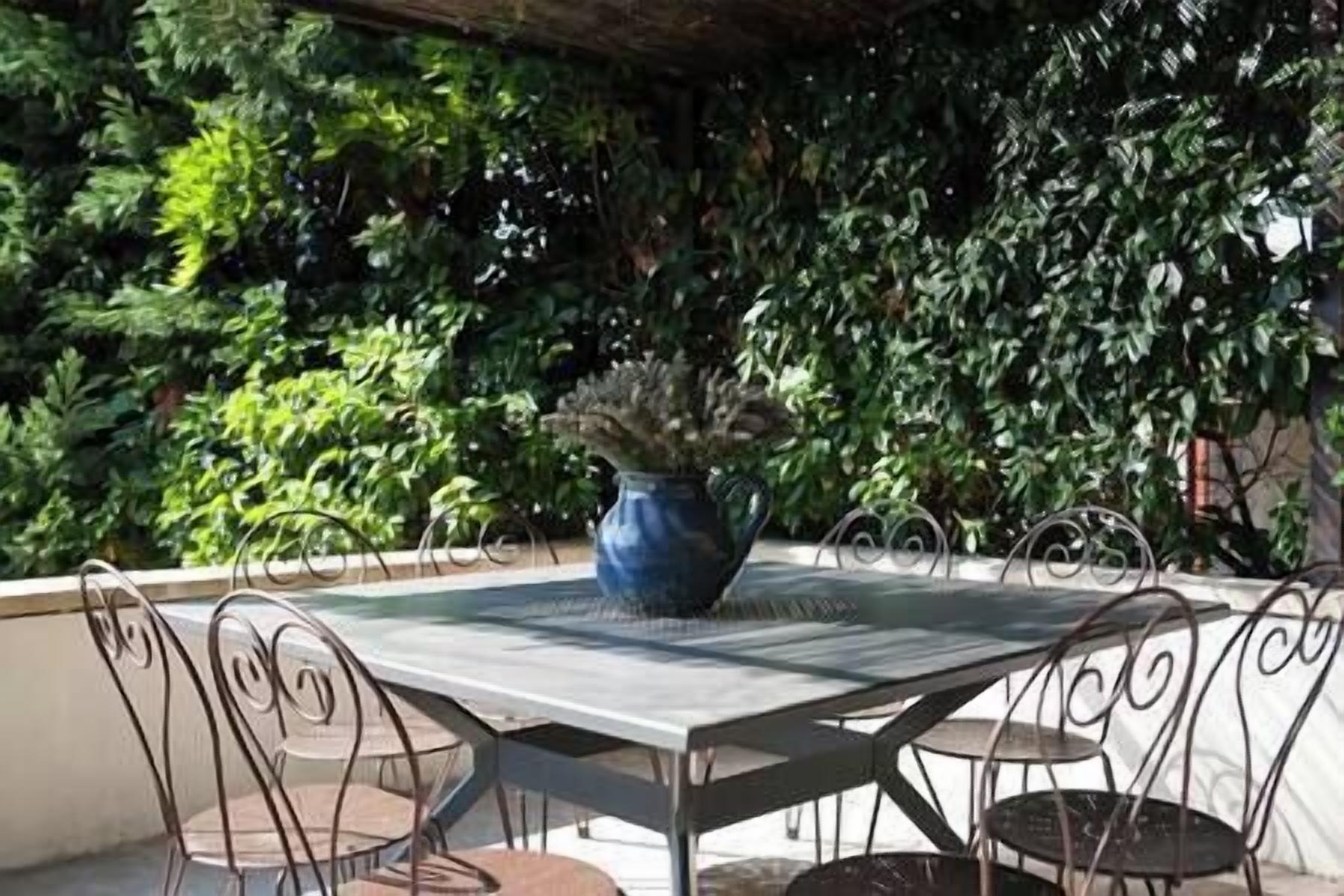 An outdoor patio with a table and chairs, surrounded by dense foliage.