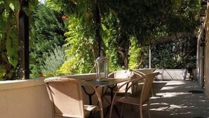 An outdoor patio with wicker furniture and a lantern. - Le Bonheur dans notre pré - Castelnaud, charming gite in an old farm (Sainte-Mondane)