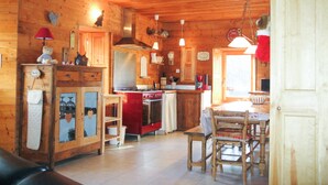 A cozy cabin-style kitchen with wooden walls, a central island, and a dining area with a table and chairs.