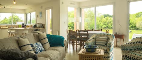 A spacious living area with a sofa, armchairs, and a dining table.