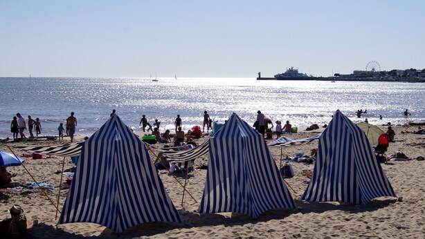 A beach with striped tents and people enjoying the shore. - Villa in Royan Park, 15 pers. - 200m from beach - 400m from shops/station. (Royan)