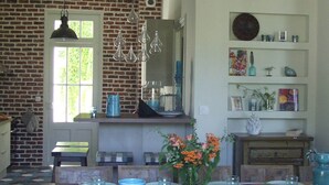 A dining area with a brick wall, wooden furniture, and a hanging light fixture. - Villa in Royan Park, 15 pers. - 200m from beach - 400m from shops/station. (Royan)