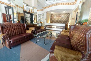 Un hall de hotel con sofás de cuero, una mesa de centro y un mostrador de recepción.