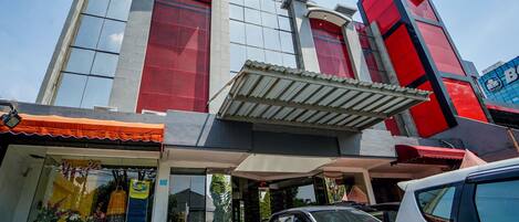 A building with a prominent 'OYO' sign, a covered entrance, and parked vehicles.