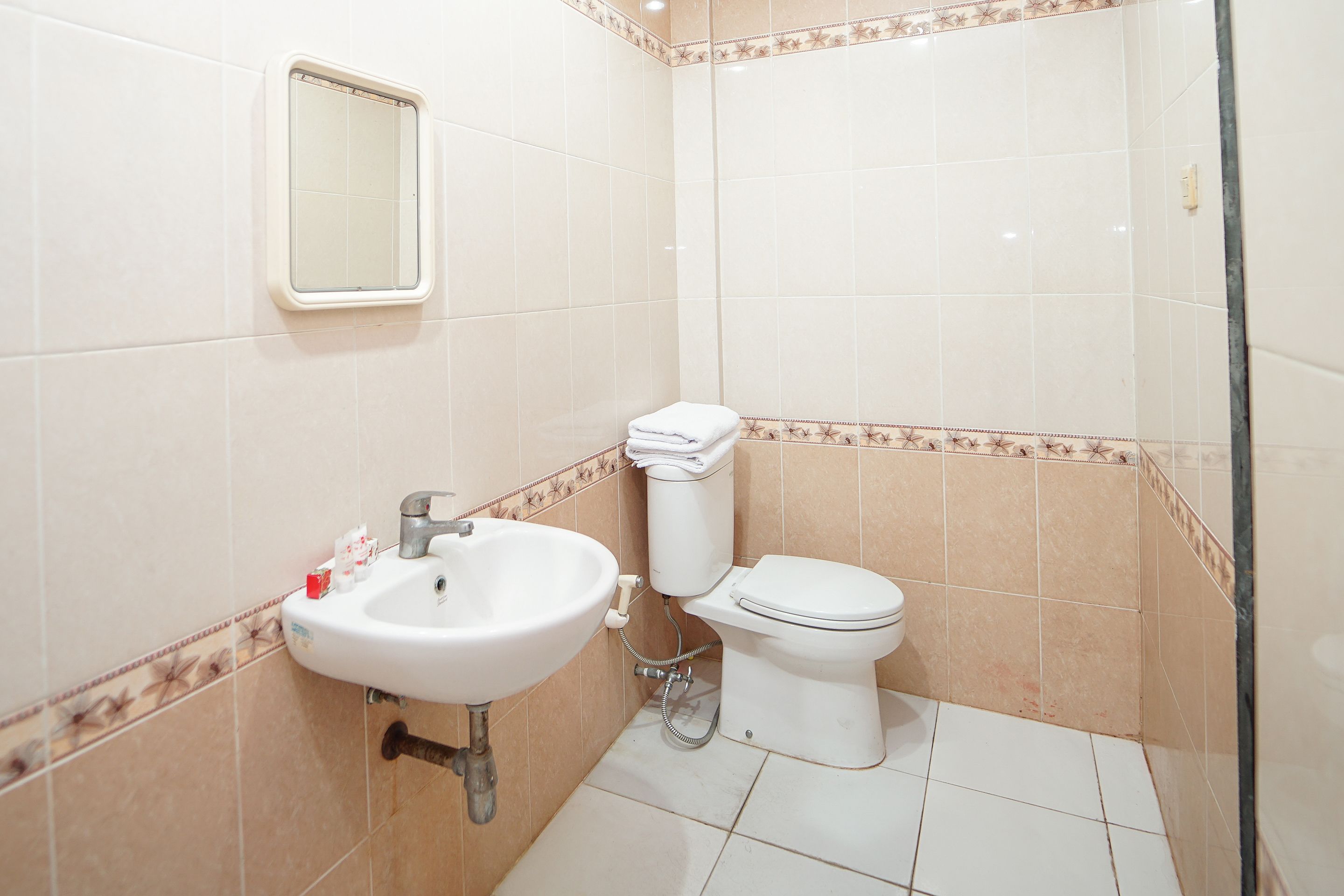 Une salle de bain avec un lavabo, des toilettes et un petit miroir.