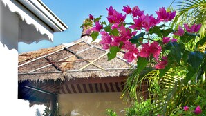 A thatched-roof structure with a bench and a small garden area with pink flowers. - New! Villa Uhaïna, Zen and atypical (SAINT-FRANÇOIS)