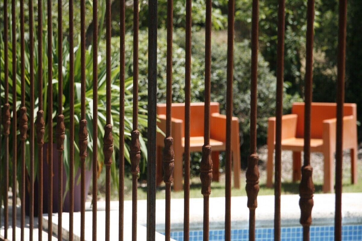 A poolside area with a wooden fence and orange chairs.
