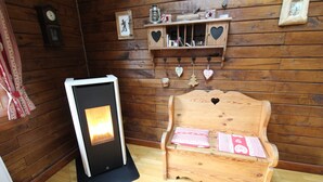 Una habitación de madera con chimenea, un banco de madera con cojín y adornos con forma de corazón en la pared.