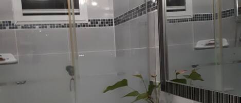 Un baño moderno con un lavamanos blanco, un espejo grande y una planta en maceta.