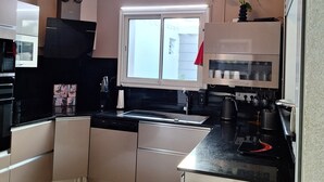 Une cuisine moderne avec des armoires blanches, un comptoir noir et un luminaire au plafond original.