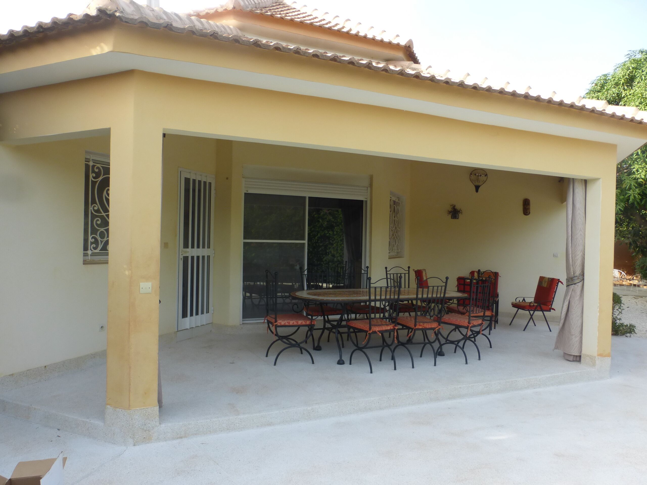 A covered patio area with a dining table and chairs, a sliding glass door, and a small decorative item on the wall.