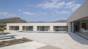 Un bâtiment moderne doté de grandes fenêtres et d’un toit plat, entouré d’un espace paysager agrémenté d’un banc et de plantes.
