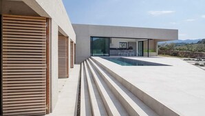 Une maison moderne dotée d’une piscine, d’un espace salon extérieur et offrant une vue sur les montagnes.