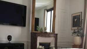 Une chambre avec un grand lit, une cheminée, une télévision et une table en marbre.