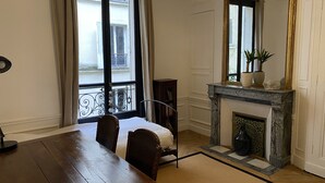 Une salle à manger avec une table en bois, des chaises, une cheminée et un grand miroir.