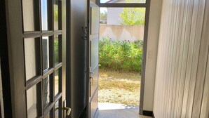 A hallway with a door leading to a garden area. - House 10 mn walk from the city center with shaded garden, olive trees.  (Uzès)