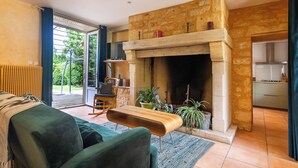 Una sala de estar con chimenea, un sofá, una mesita de centro y vistas al exterior.