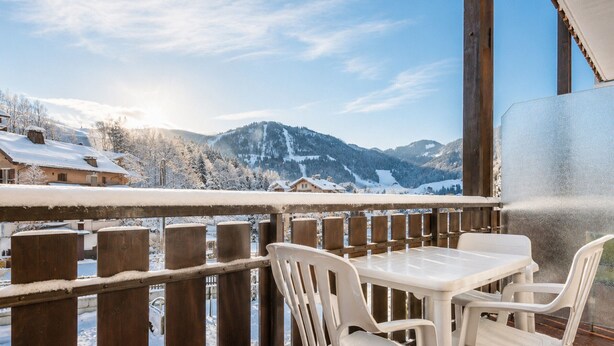 Een balkon met uitzicht op besneeuwde bergen en huizen.