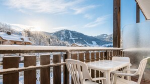 Un balcon avec vue sur des montagnes et des maisons enneigées.