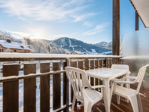 A balcony with a view of snow-covered mountains and houses.