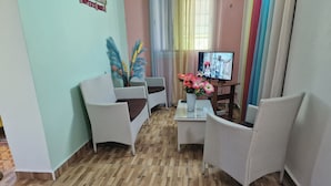 A room with wicker furniture, a television, and a window with curtains. - Detached house rated 03 stars, comfortable, equipped, with Wifi (deshaies)