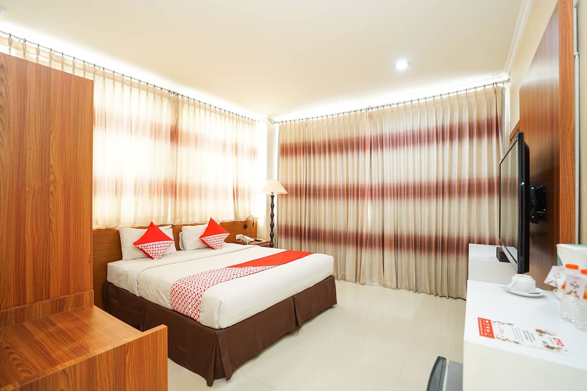 A hotel room with a bed, a desk, a television, and curtains.