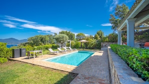 A swimming pool with lounge chairs, a table, and a pergola. - Magnificent villa at the gates of Saint-Tropez (Gassin)