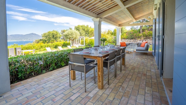 A covered patio with a table set for dining, outdoor seating, and a view of the landscape. - Magnificent villa at the gates of Saint-Tropez (Gassin)