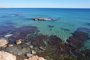 A coastal view with clear water, rocky formations, and distant shoreline.