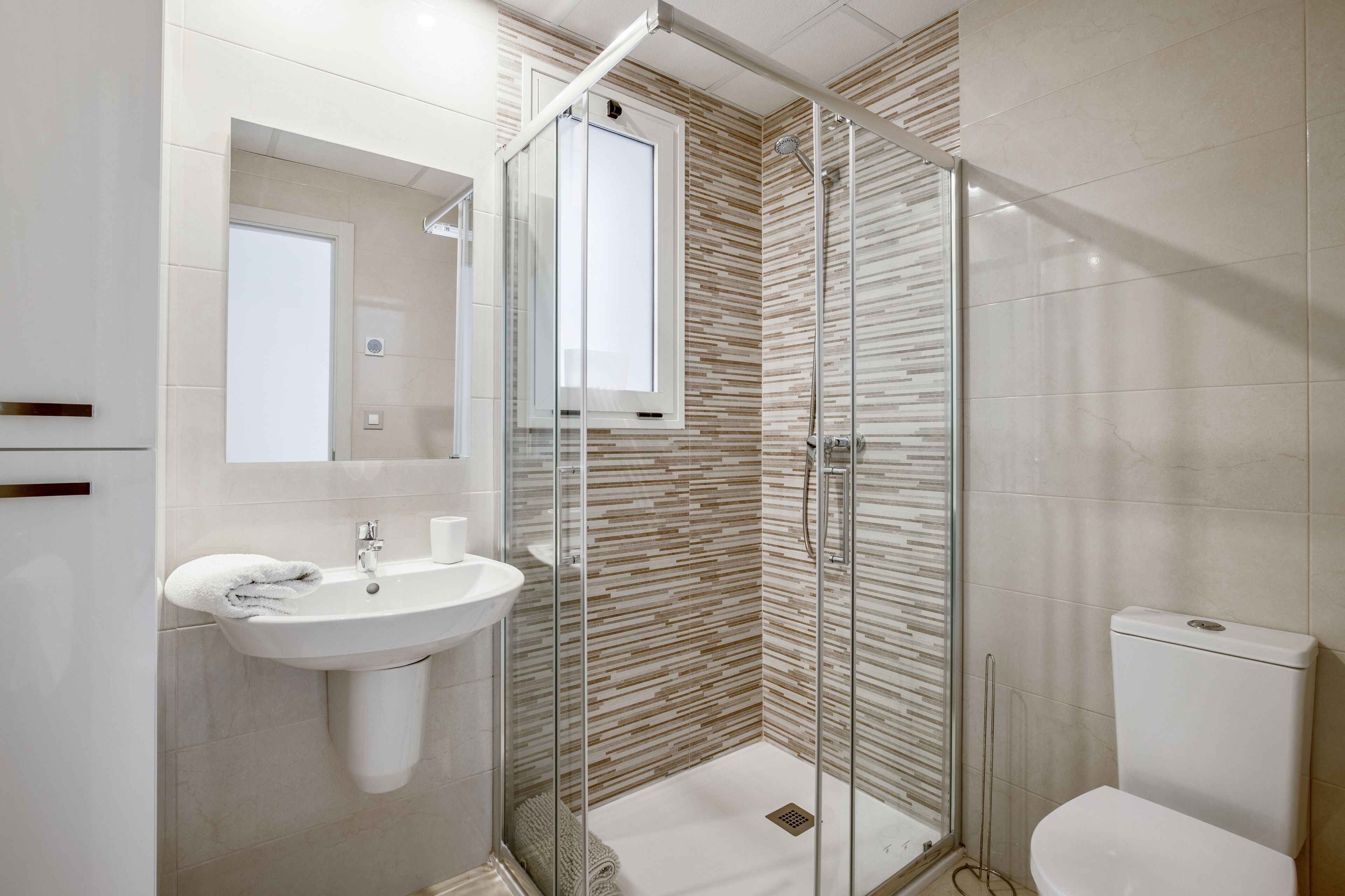A modern bathroom with a glass-enclosed shower, a sink, and a toilet.