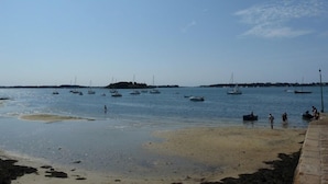 A beach with boats and people.