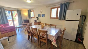 Un rincón comedor acogedor con una mesa y sillas de madera, un sofá y un refrigerador.