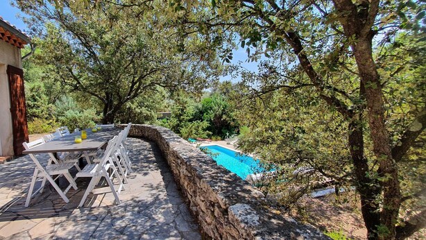 A stone patio with a table and chairs, a swimming pool, and a stone wall. - Villa sleeps 8 with superb pool   (La Tour-D'aigues)