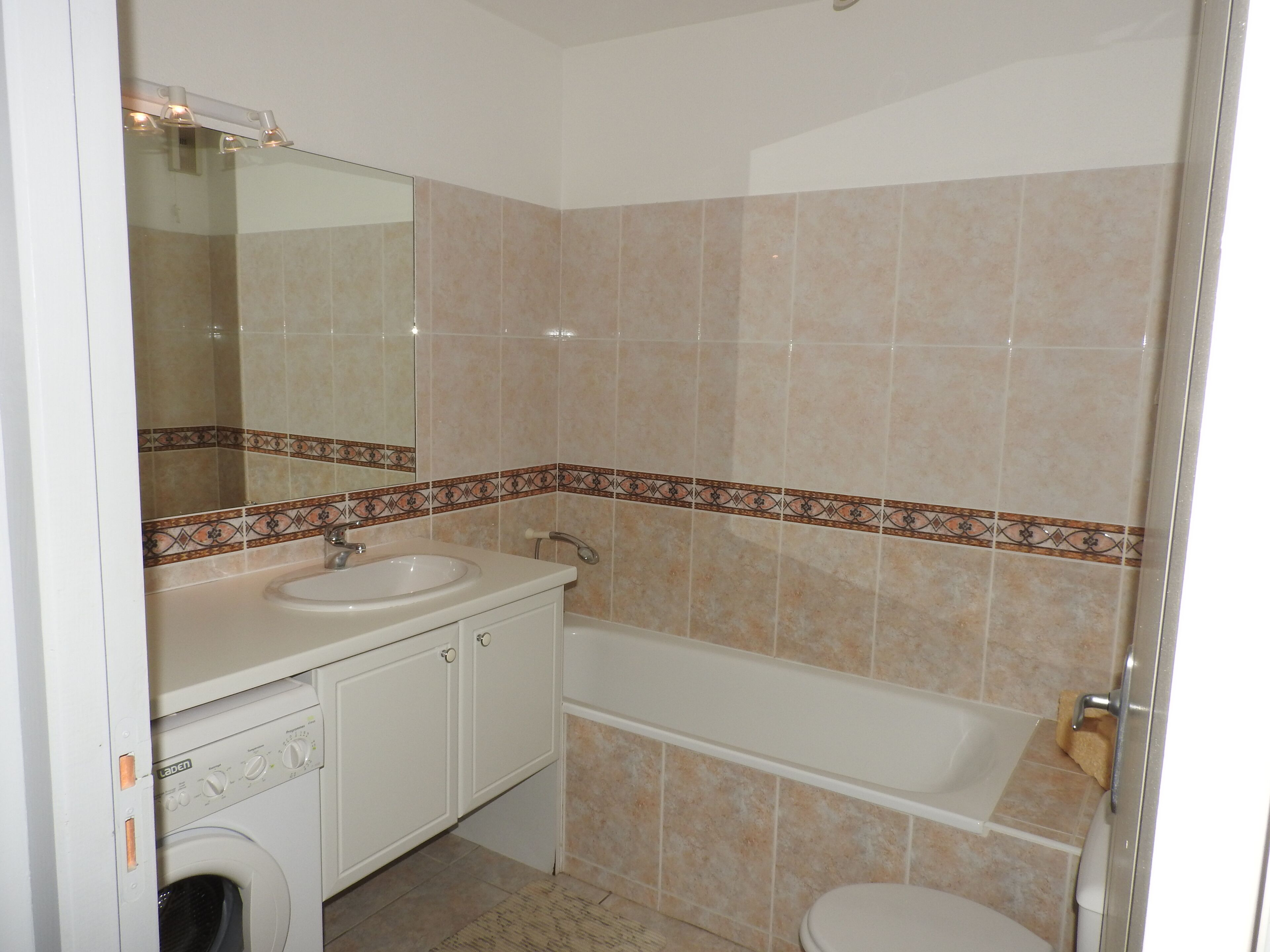 A bathroom with a sink, mirror, toilet, and bathtub.
