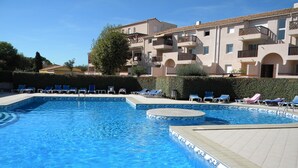 A swimming pool with blue tiles and a tiled deck area. There are lounge chairs and a hedge in the background. - 54m² apartment rental with view of boats, shaded and sunny St Cyprien (Pyrénées-Orientales)