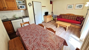 Un espace de vie compact comprenant un coin repas, une kitchenette et un canapé.