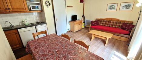 A compact living space with a dining area, kitchenette, and a sofa.