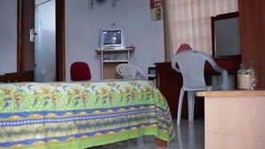 A bedroom with a bed, a desk, a chair, a TV, and an air conditioning unit. - Your bed and breakfast, Tamarind, 5 minutes from the beach and the center (Flic en Flac)