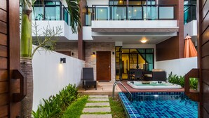 Un moderno edificio de dos pisos con piscina, jacuzzi y una escalera que conduce a la entrada.