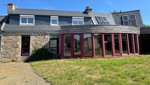 A two-story house with a stone facade, a red door, and a conservatory with glass doors. - Charming house, quiet and bright in the heart of Trébeurden (4 bedrooms) (Trébeurden)