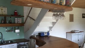 A kitchen with a wooden bar counter, shelves with canned goods, and a radio. - Charming house, quiet and bright in the heart of Trébeurden (4 bedrooms) (Trébeurden)