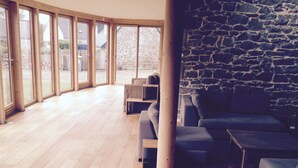 A spacious room with wooden flooring, a stone wall, and large windows. - Charming house, quiet and bright in the heart of Trébeurden (4 bedrooms) (Trébeurden)