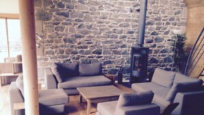 A cozy living room with a stone wall, a fireplace, and modern furniture. - Charming house, quiet and bright in the heart of Trébeurden (4 bedrooms) (Trébeurden)
